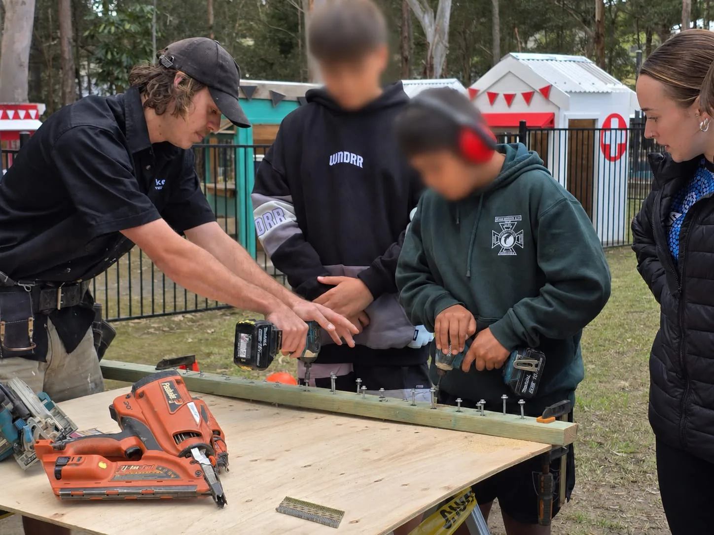Akers Construction carpenter showing a student how to drive fixings with an impact driver