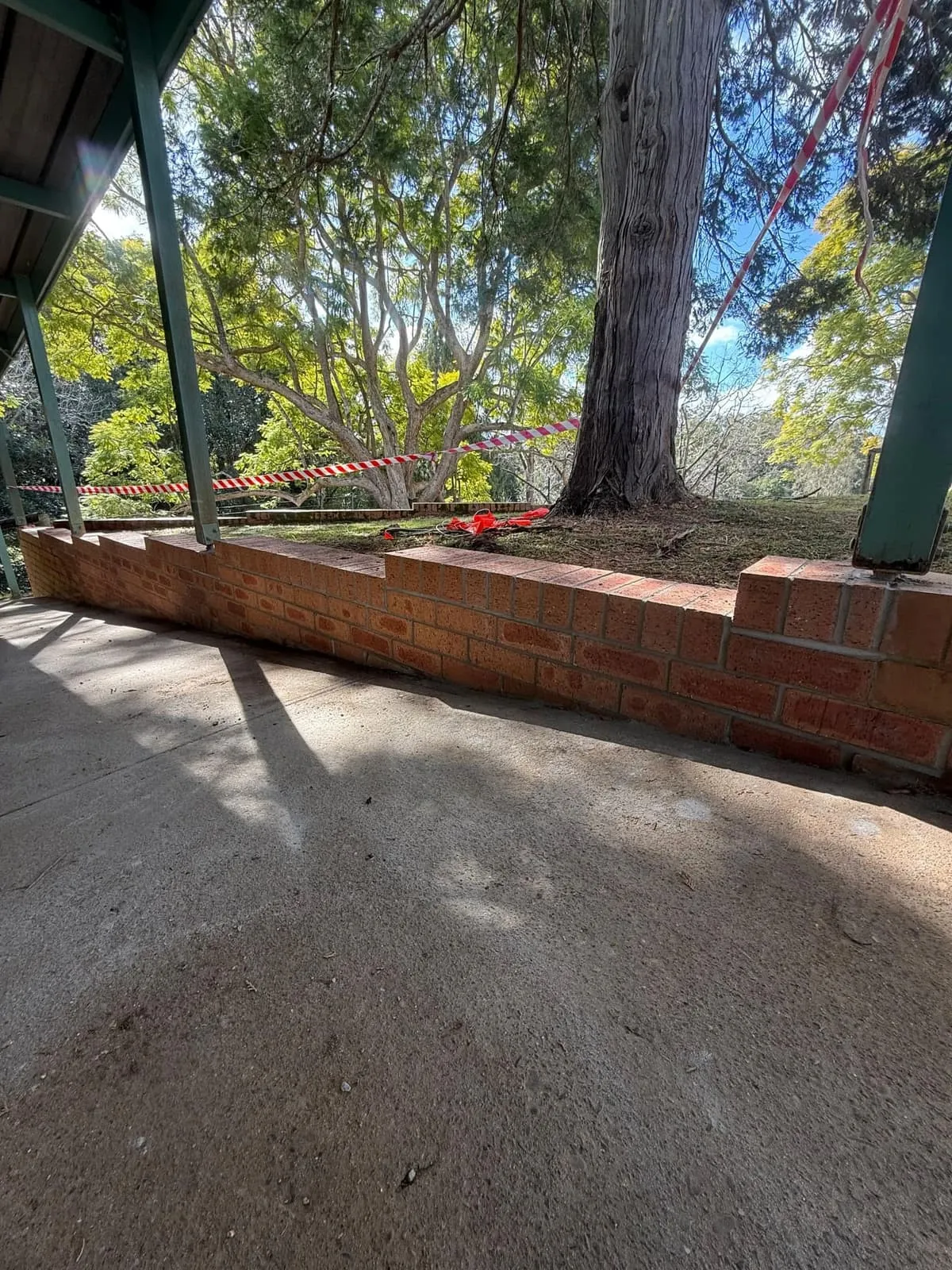 Brick garden bed retaining wall built under established trees at Bellingen High School