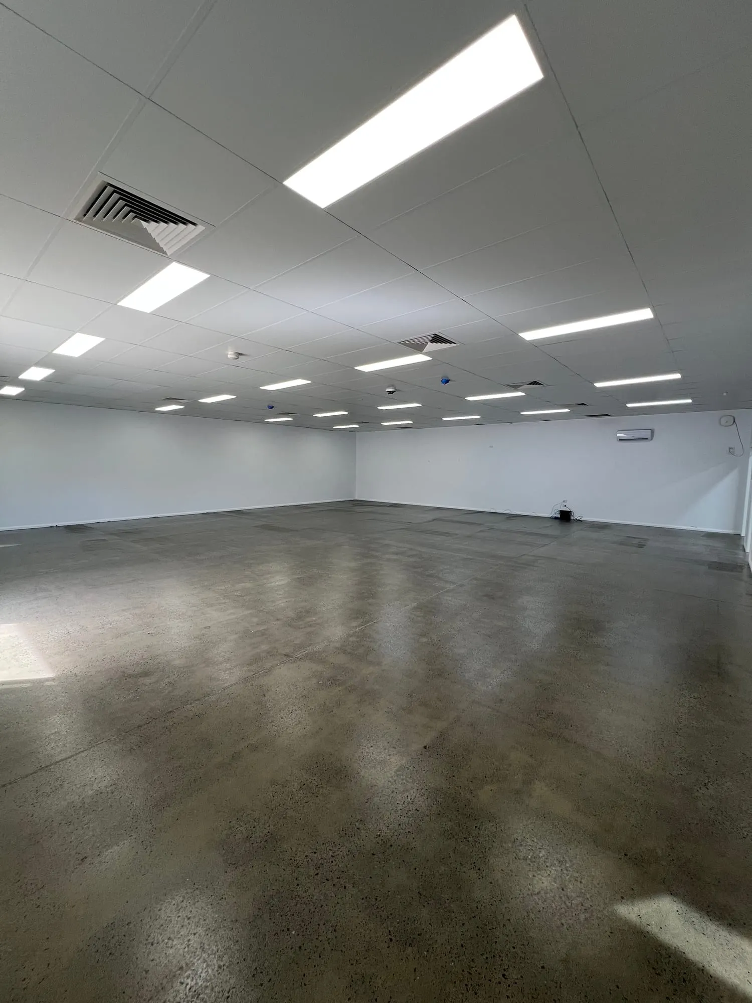 Empty commercial retail tenancy with polished concrete floor, ready for fit-out