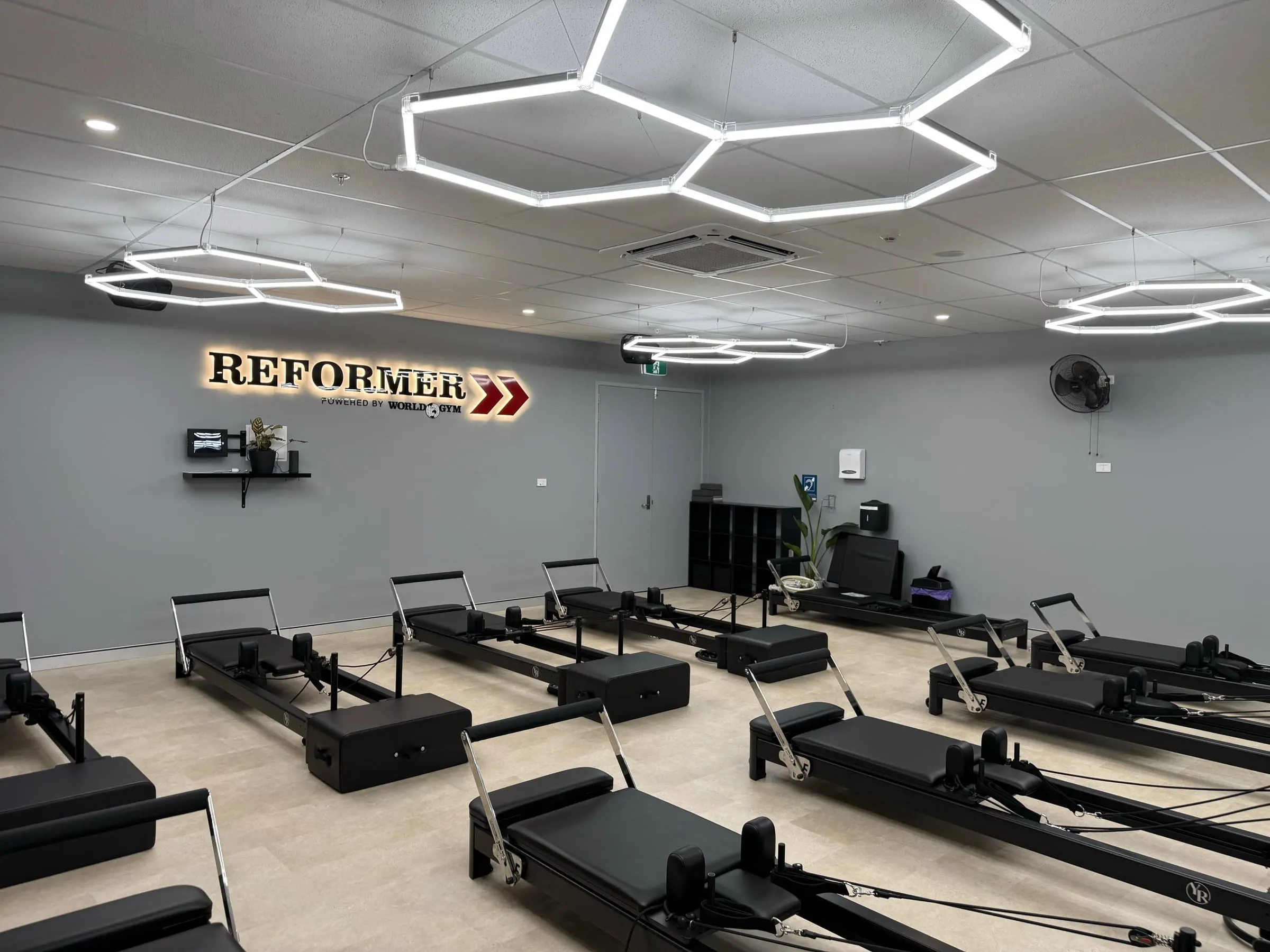 Reformer pilates studio fit-out at World Gym Coffs Harbour under hexagon feature lighting