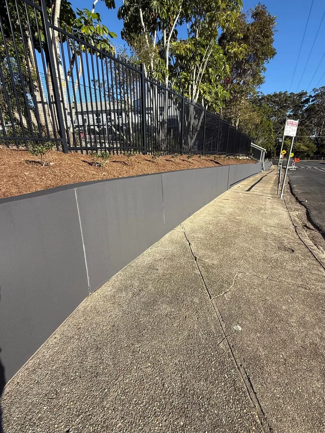 Curved rendered retaining wall following the footpath to the school entrance, Nambucca Heads