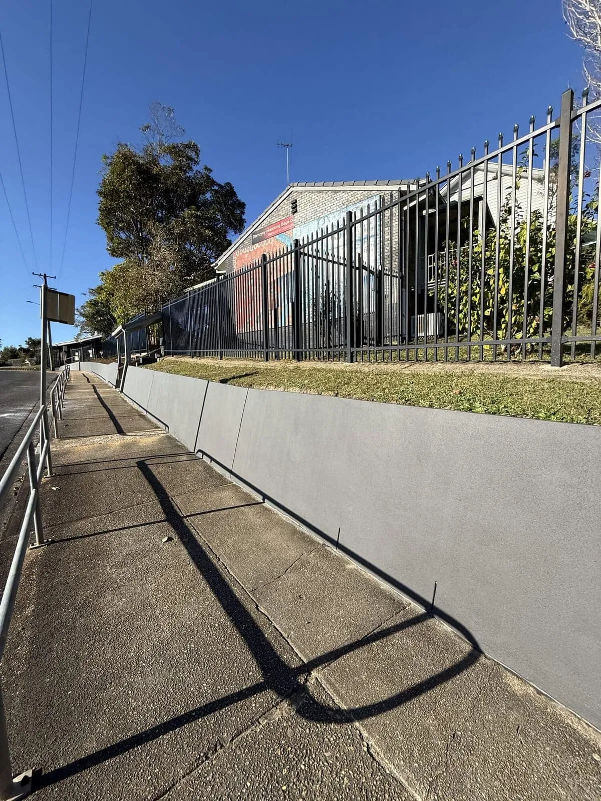 Rendered retaining wall and steel palisade fence along the school frontage, Nambucca Heads