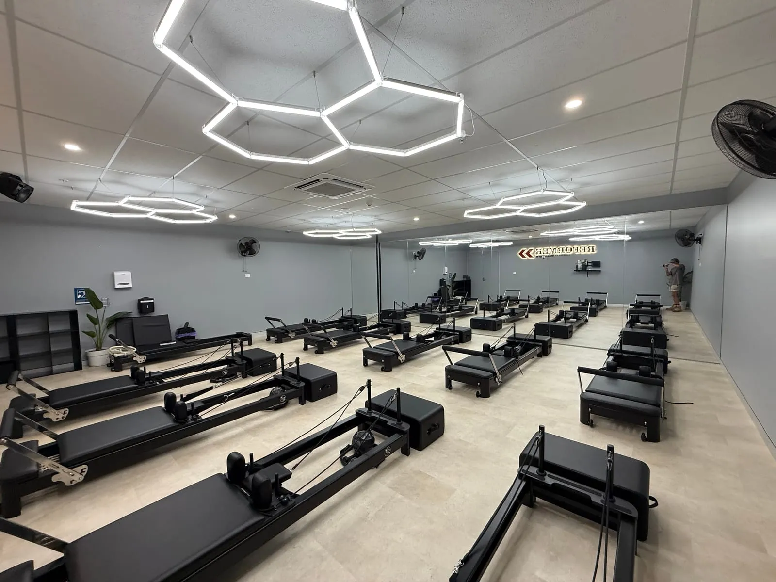 Rows of reformer equipment under hexagon lighting at World Gym Coffs Harbour